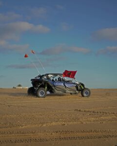 Off-road vehicle driving through sand dunes in Tangier, Morocco under clear blue skies.