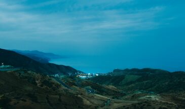 A breathtaking coastal landscape of El Jebha, Morocco, at dusk featuring winding roads and serene ocean views.