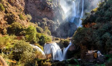 Stunning multi-tiered waterfalls cascading through mossy rocks in a lush forest setting under daylight.