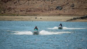 Two people enjoy thrilling jet ski rides on a sunny lake, perfect for adventure.