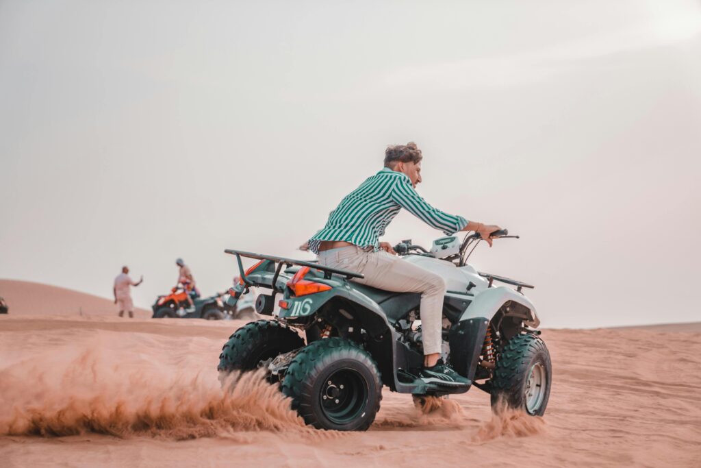 Man on an ATV enjoying a thrilling ride across desert sands.