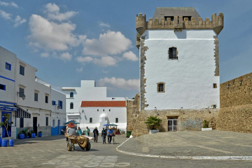 A white building with a clock tower in the middle of a town