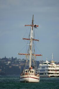 Tall sailing ship and modern yacht in a serene harbor setting, perfect for maritime themes.