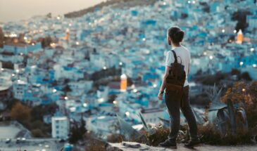 Traveler overlooks the blue city of Chefchaouen at dusk, capturing the vibrant essence of this Moroccan gem.