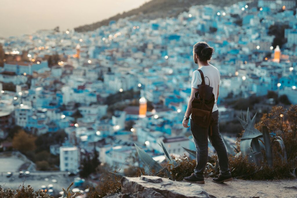 Traveler overlooks the blue city of Chefchaouen at dusk, capturing the vibrant essence of this Moroccan gem.