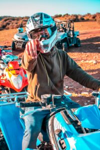 A man wearing a helmet rides a quad bike in the Moroccan desert, showcasing adventure and excitement.