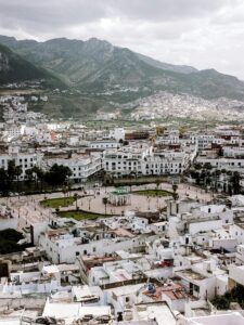 Aerial view of Tetouan cityscape with Rif Mountains in the background under cloudy skies.